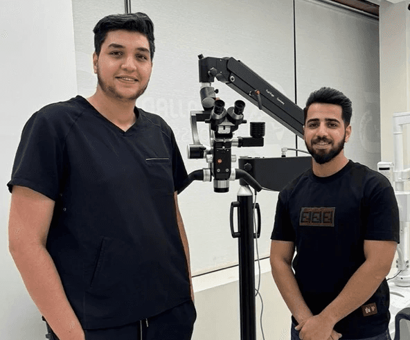 Two people next to Karl Kaps Microscopes made in Germany. Professionals smile in a clinical setting.