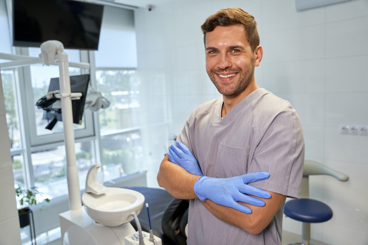 A professional stands confidently in a clinic. Medical equipment surrounds them.