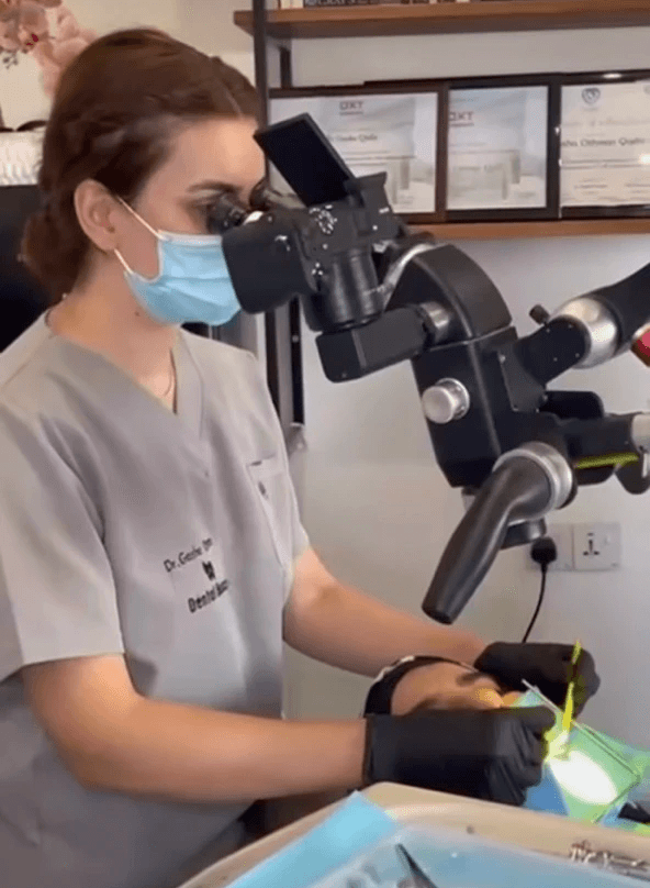 A professional uses "Karl Kaps" "Microscopes made in Germany" during a dental procedure on a patient in a
