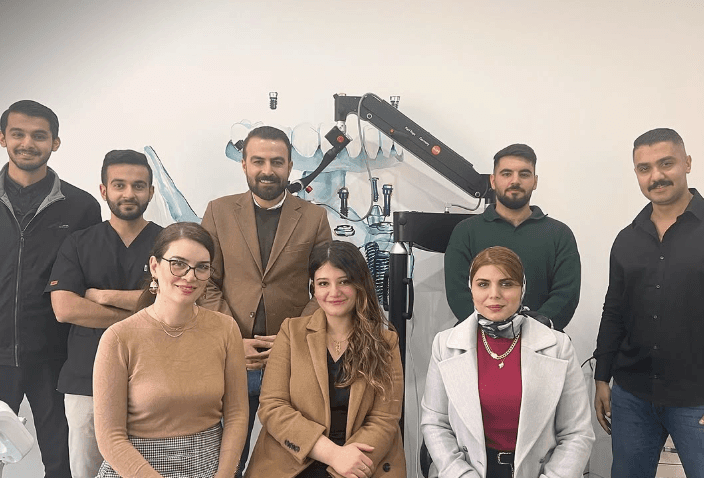 Group of professionals poses in front of dental equipment, including a Karl Kaps Microscopes made in Germany.