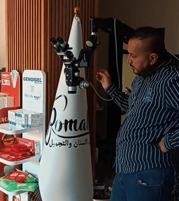 Person inspects Karl Kaps "Microscopes made in Germany" atop cone.  Shelf of dental products nearby.