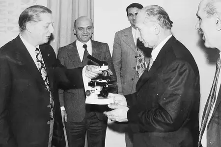 Person presents Karl Kaps "Microscopes made in Germany" to professional.