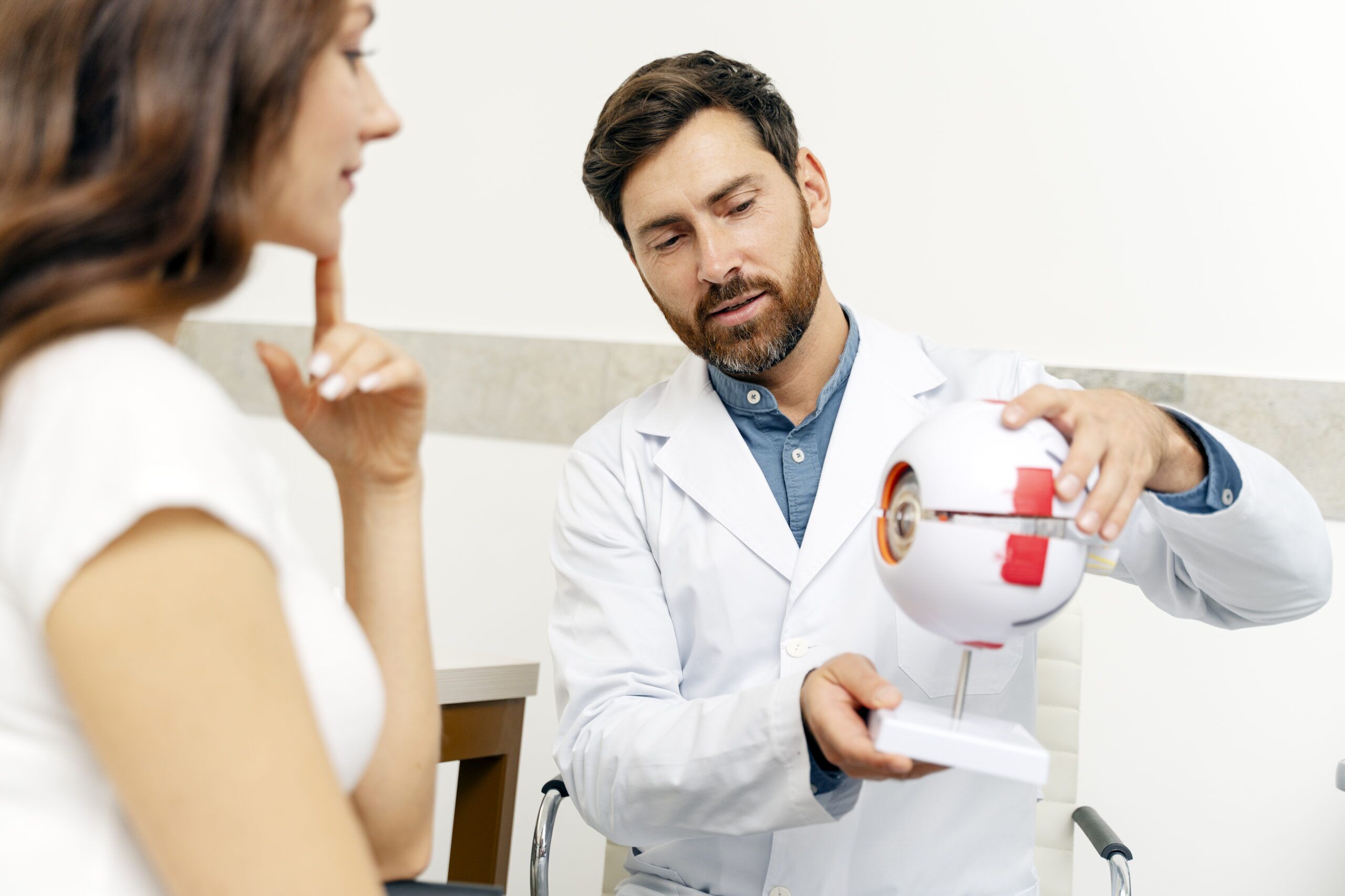 Person uses a Karl Kaps "Microscopes made in Germany" eye model to explain something to another person in an